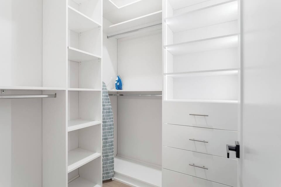 Spacious walk-in closet with built-in shelving, drawers, and hanging space to keep your wardrobe organized. Includes an ironing board and iron for added convenience during your stay.
