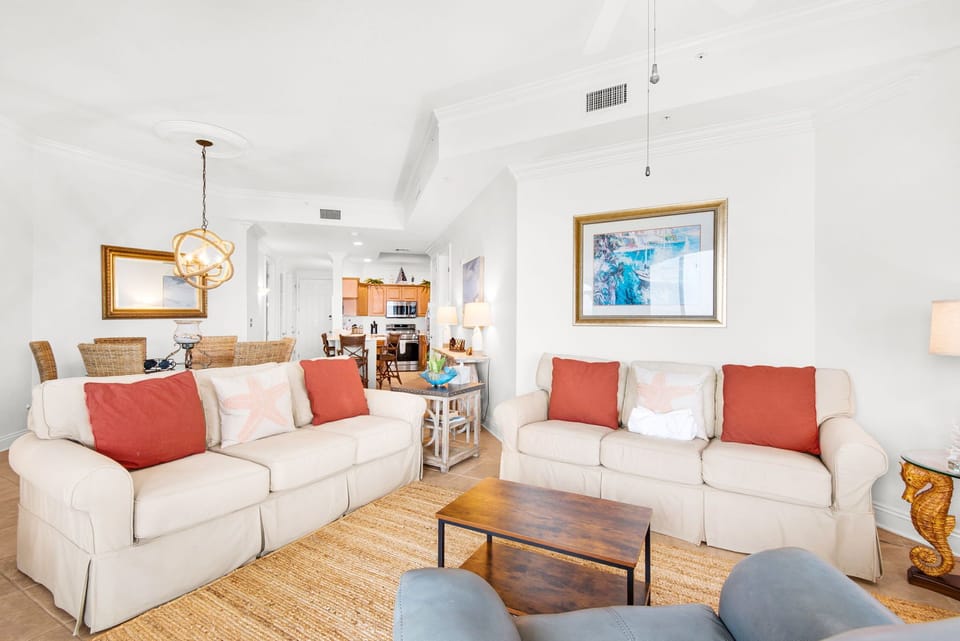 Sink into plush seating where natural textures and pops of coral invite you to unwind after sun-soaked beach days.