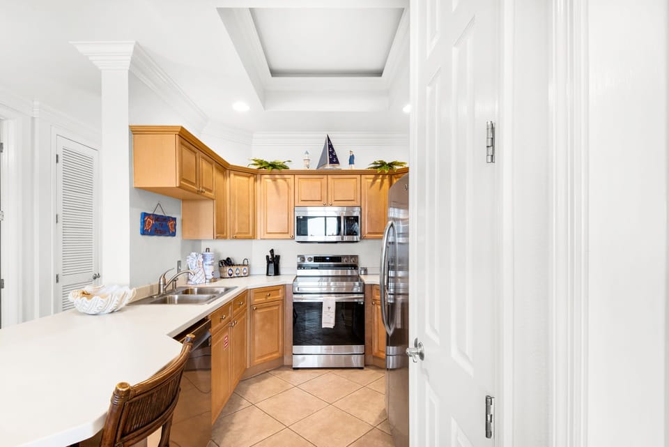 Your fully equipped kitchen awaits with warm wood cabinetry, stainless steel appliances, and a breakfast bar.