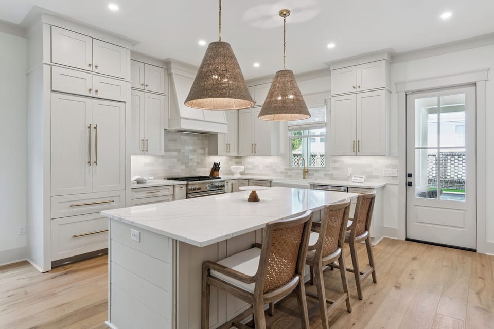 Picture yourself preparing meals in this bright, chef-inspired kitchen with elegant white cabinetry, a spacious island for gathering, and warm woven pendant lights creating the perfect welcoming ambiance.