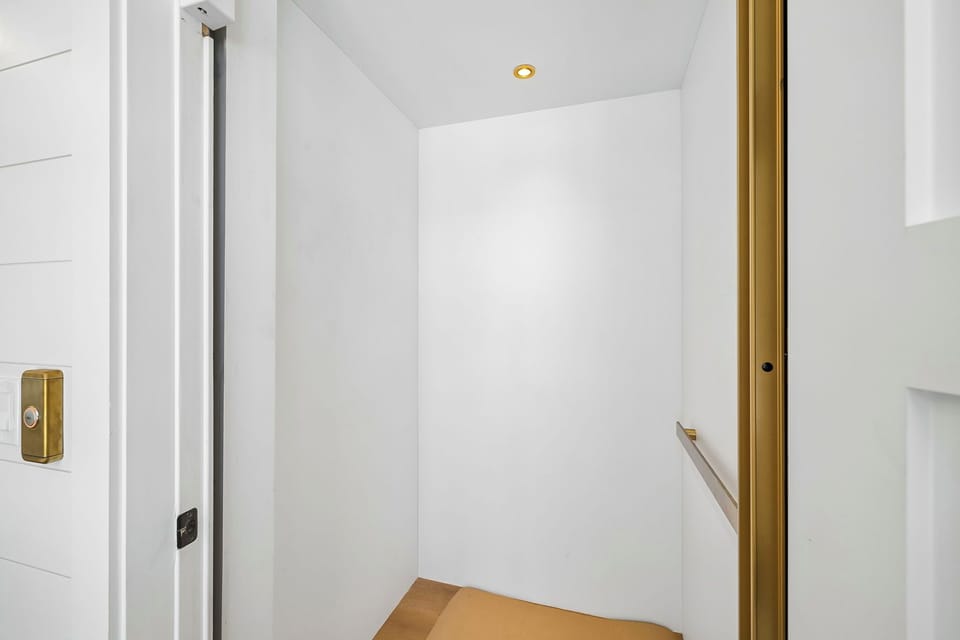 A bright, modern stairwell with clean white walls and elegant brass details guides you between levels of this thoughtfully designed space.