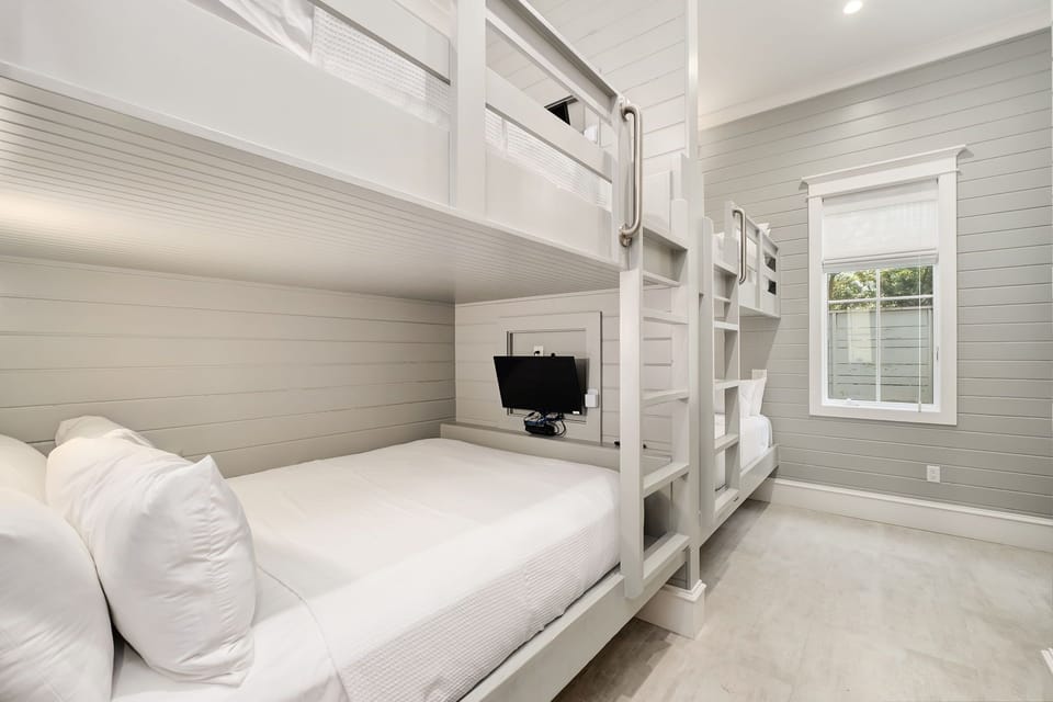 Drift off in this cozy bunk room where crisp white linens and soft coastal tones invite restful sleep for your whole crew.