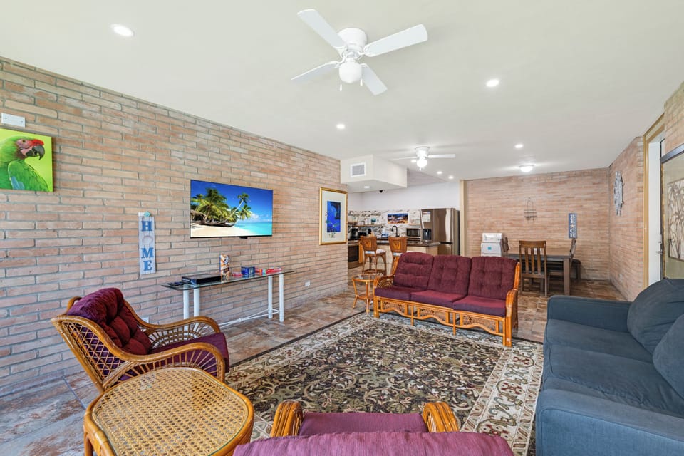 Unwind in this spacious living area, where exposed brick walls meet tropical comfort. Ceiling fans and bright lighting create an airy, welcoming atmosphere for your stay.