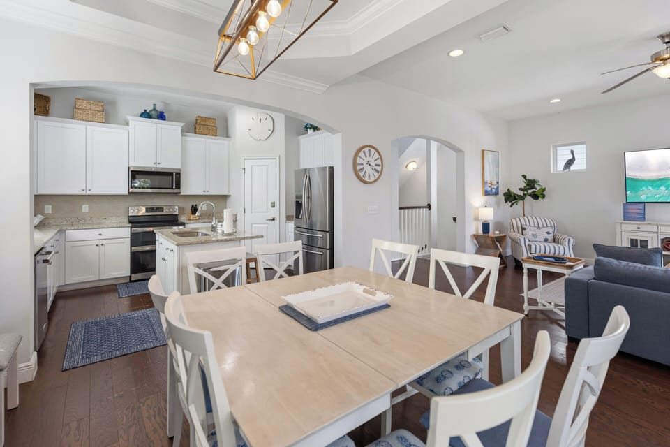 Gather around this inviting open-concept space where bright coastal charm meets comfort. Your kitchen flows effortlessly into dining and living areas, perfect for shared meals and relaxed evenings together.