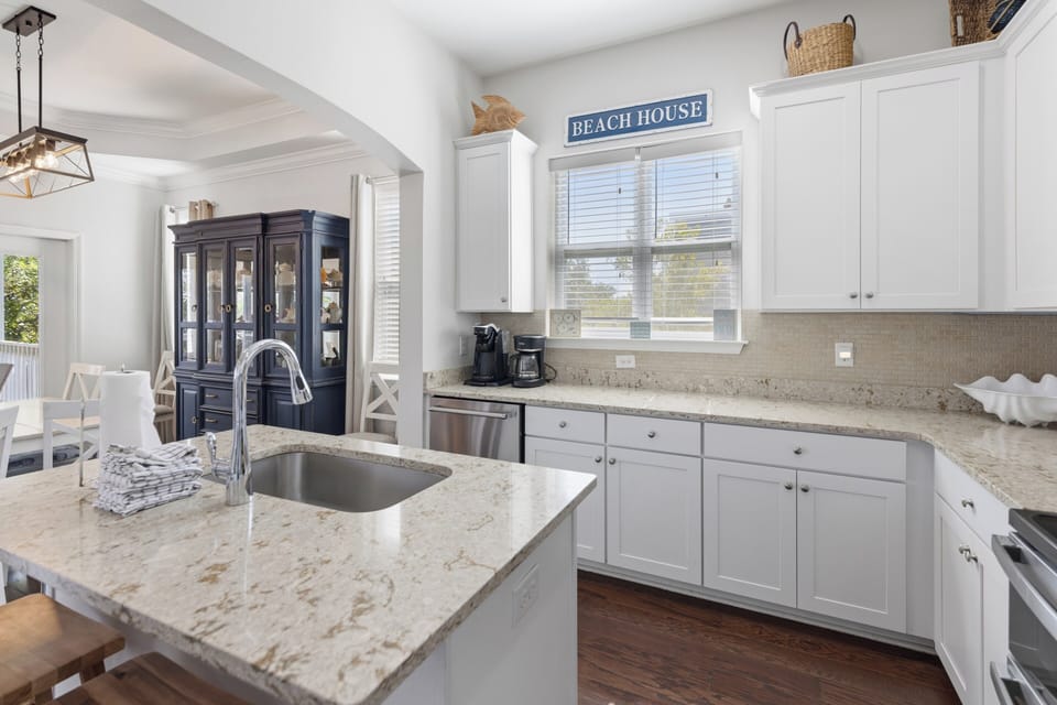 Your coastal retreat awaits in this bright, airy kitchen with gleaming granite counters, stainless appliances, and charming beach house touches that set the perfect vacation mood.