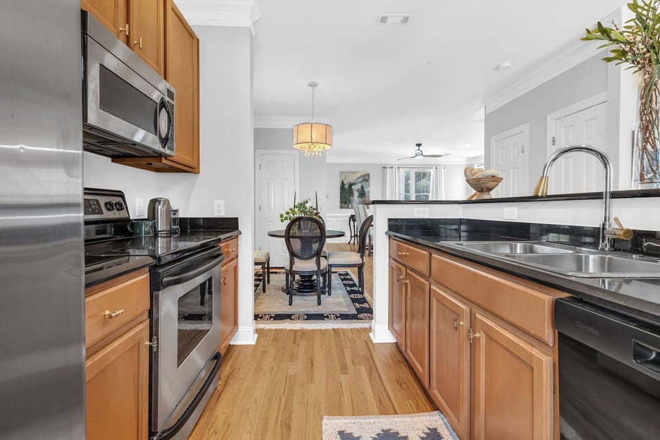 Bright galley kitchen with stainless appliances and dining area