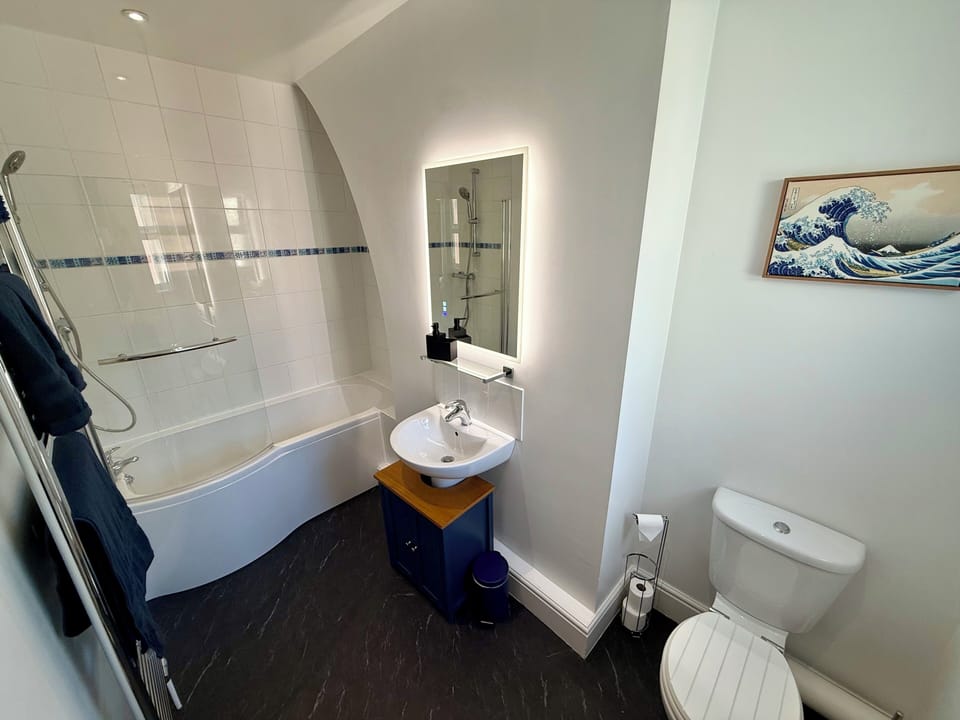 Bright modern bathroom with tub, shower, and illuminated mirror