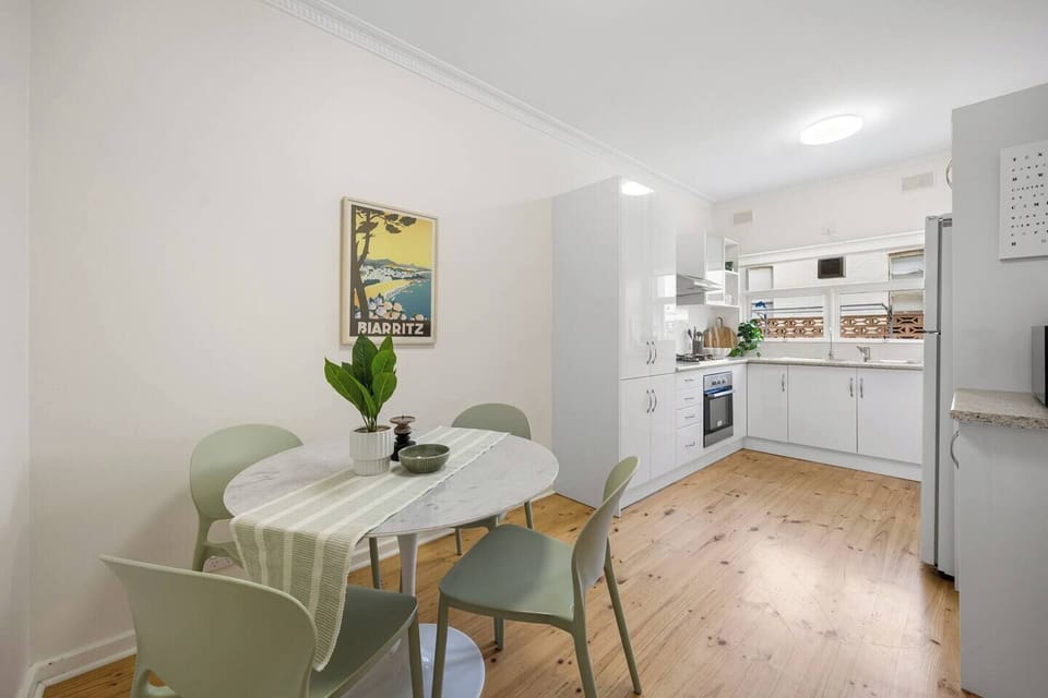 Gather around the dining table for casual meals and easy conversation beneath the coastal-inspired artwork, reflecting the beachside atmosphere that surrounds the apartment.