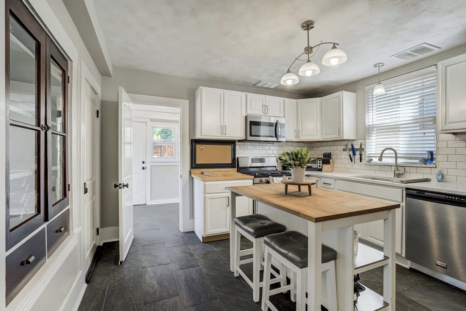 The fully stocked kitchen includes cookware, dishes, full-size appliances, dishwasher, kitchen island seating, and a coffee bar with starter coffee provided.