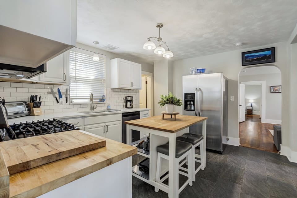 The fully stocked kitchen includes cookware, dishes, full-size appliances, dishwasher, kitchen island seating, and a coffee bar with starter coffee provided.