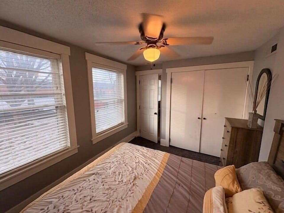 Sunny bedroom with ceiling fan, double closet, and cozy bedding