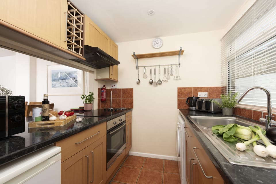 Kitchen with microwave, cooking facilities and sink - Porth Beach House