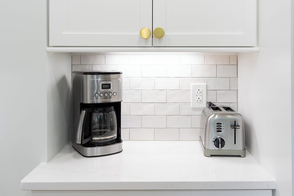 A dedicated countertop coffee nook houses the standard carafe coffee maker and a matching stainless-steel toaster, neatly tucked underneath the white cabinetry.