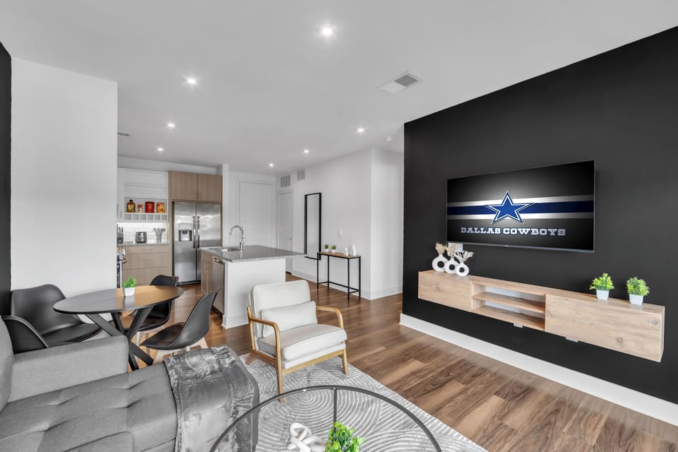 Modern open-concept living space with sleek kitchen and large TV