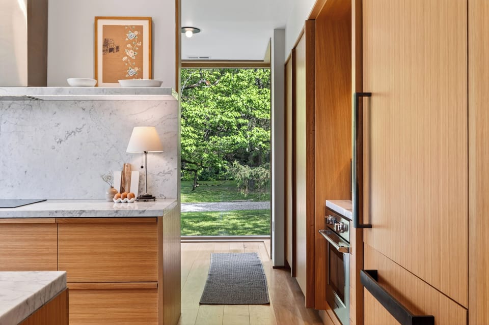 Seamless indoor-outdoor flow highlights this kitchen walkway, opening directly onto lush greenery.