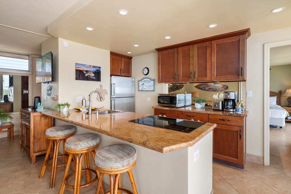 Modern kitchen with granite countertops, stainless appliances, and a breakfast bar with seating for three for easy dining.