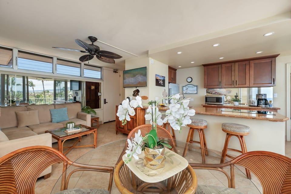 Bright interior featuring a seamless living area, breakfast bar seating, and direct views toward the oceanfront lanai.