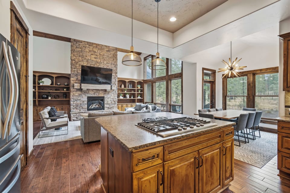 Gather around the open-concept kitchen and living area, where soaring ceilings and abundant natural light invite you to cook, relax, and take in wooded views through expansive windows.