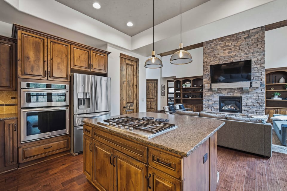 Picture yourself preparing meals in your gourmet kitchen, with rich wood cabinetry, stainless steel appliances, and a spacious island perfect for cooking and gathering. The open layout flows seamlessly to your cozy living area with a stone fireplace.