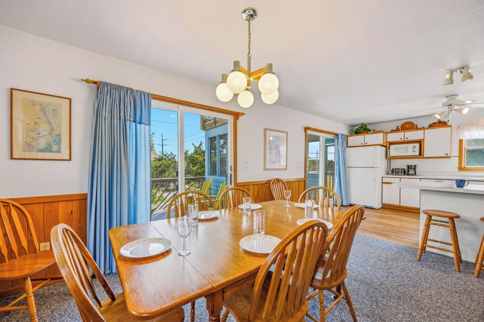 Picture gathering your group around this spacious dining table, sharing meals and laughter in a bright, welcoming space with natural light streaming through ocean-view windows.