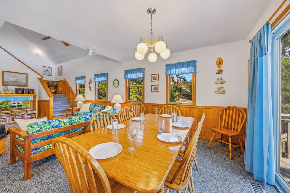 Gather around the warm wooden dining table where laughter and meals naturally flow. Sunlight pours through coastal windows, inviting you to relax and make memories in this charming nautical-themed space.
