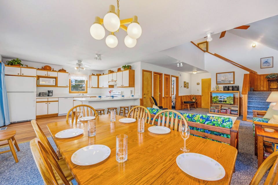 Gather around the spacious dining table where your group can share meals and make memories together. The open-plan kitchen and cozy living area create a welcoming flow for your stay.