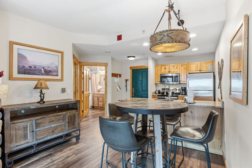 Step into your welcoming open-concept space with rustic charm and modern comforts. You'll love gathering around the round dining table under the unique pendant light, with a fully-equipped kitchen ready for your group meals.