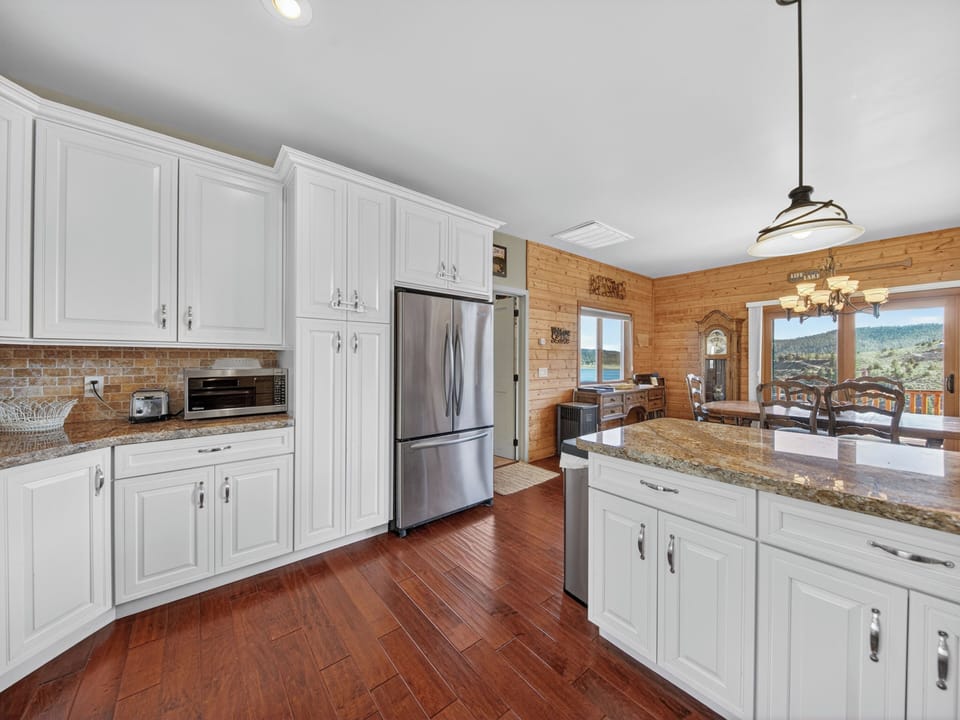 Your spacious chef's kitchen features gleaming granite counters, stainless appliances, and rich hardwood floors—perfect for preparing meals while enjoying mountain vistas through the dining room windows.