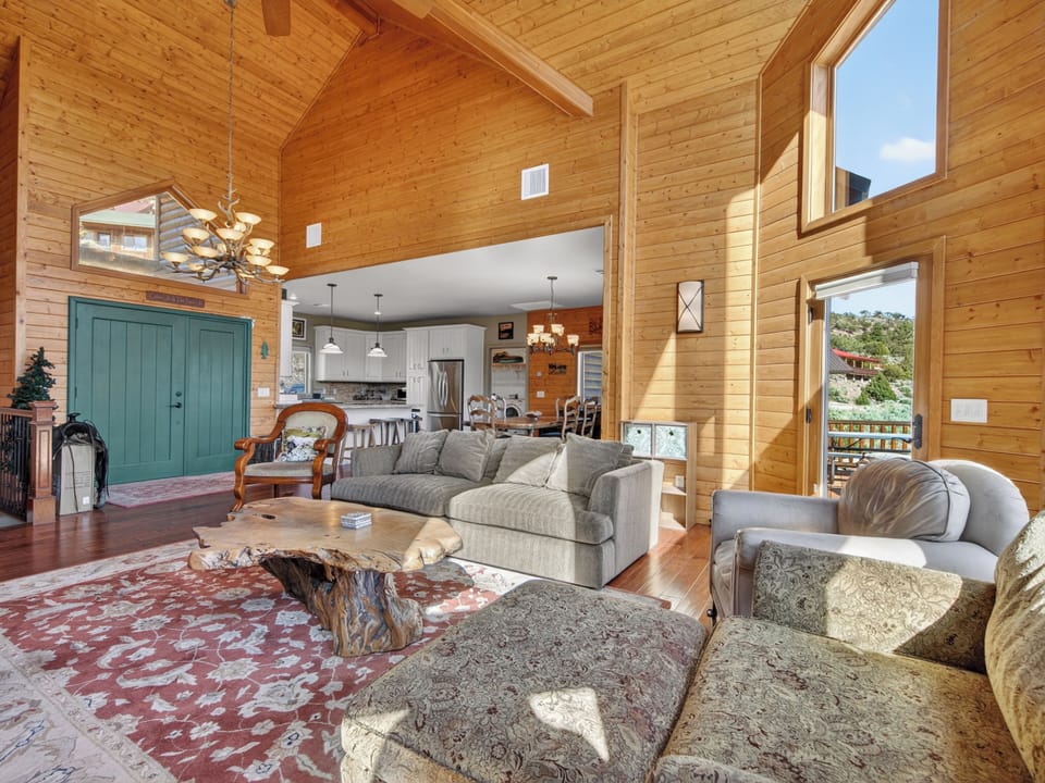 Sunlight streams through tall windows into your spacious open-concept retreat, where vaulted wood ceilings and cozy seating invite you to unwind after a day of mountain adventures.
