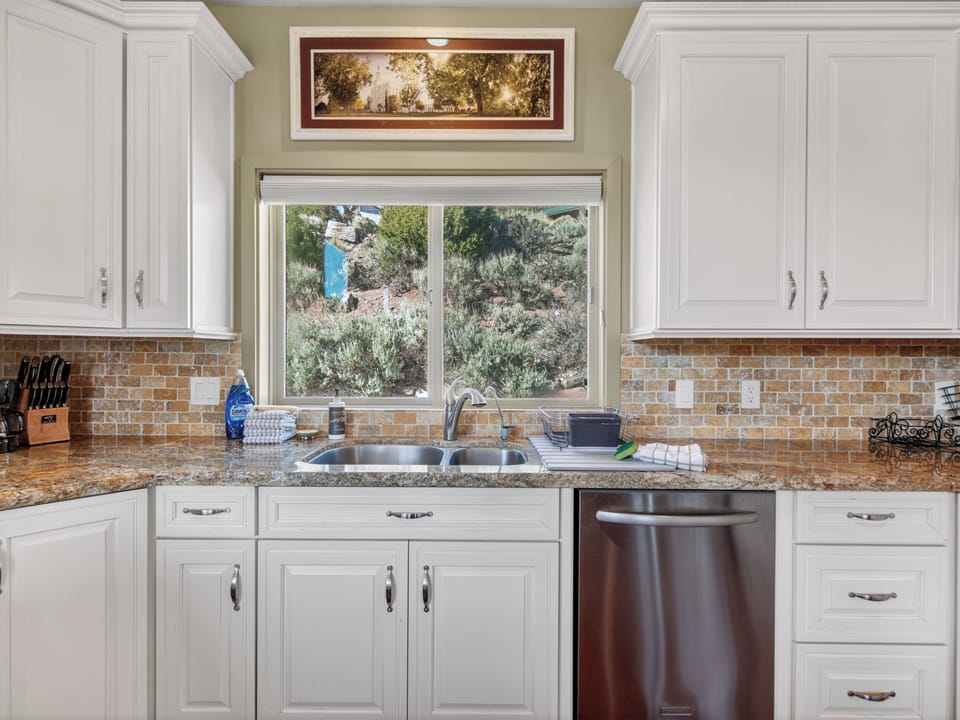Your bright, fully equipped kitchen awaits with granite counters, modern appliances, and a window framing peaceful views of natural desert landscaping—perfect for preparing meals in style.