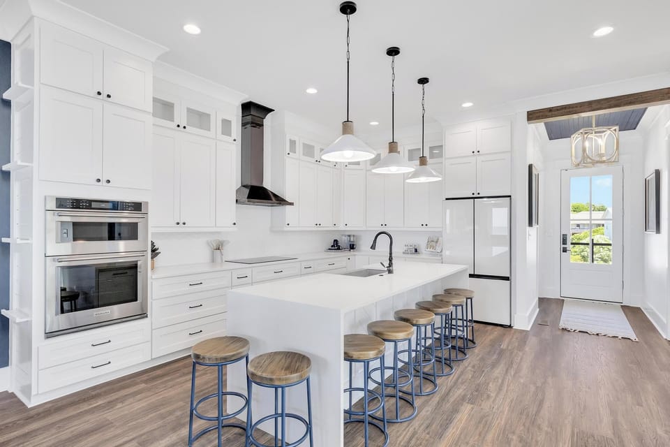 Gather around the spacious island in your open-concept kitchen, where bright white cabinetry, modern appliances, and stylish pendant lighting create an inviting space for cooking and connecting.