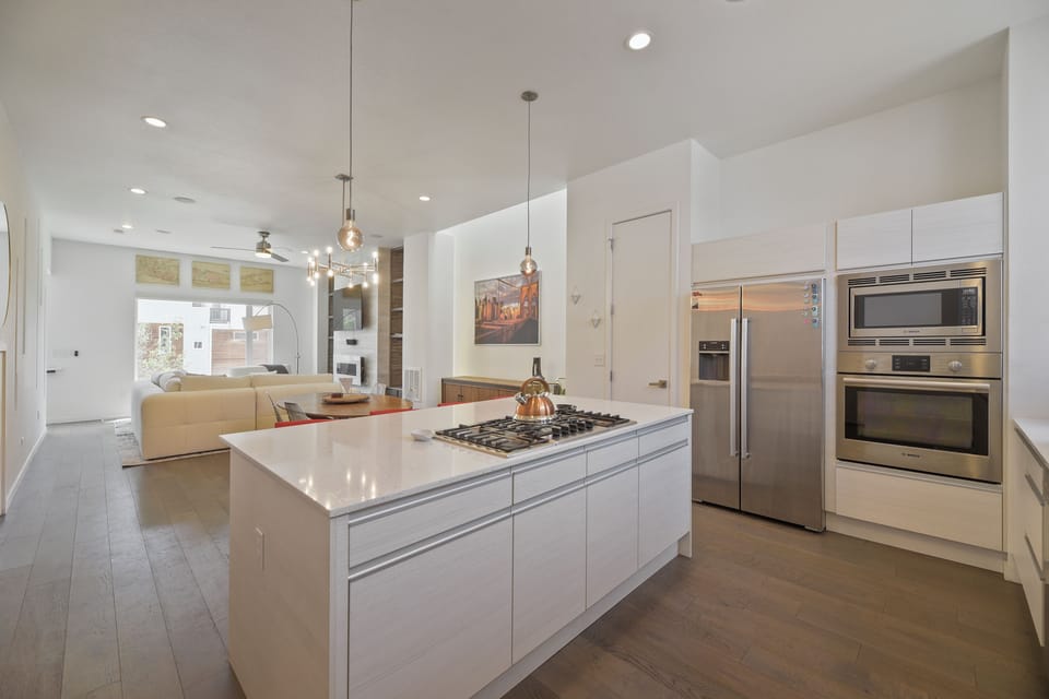 Step into your sleek, modern kitchen where gleaming white cabinetry, stainless steel appliances, and a spacious island invite you to cook, gather, and create lasting memories.