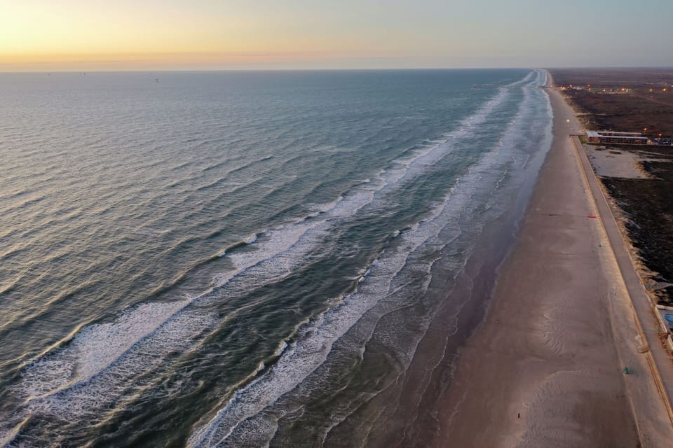 Stunning aerial view captures miles of pristine coastline stretching into the distance at golden hour.
