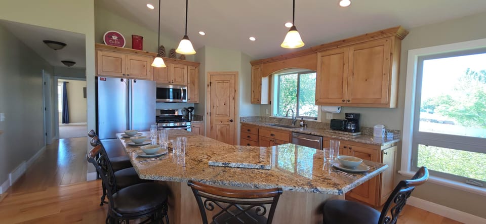 Bright gourmet kitchen with granite island, bar seating, and sunny windows