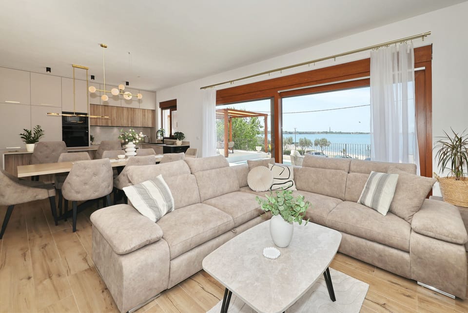 Open living area of Villa Diaria with comfortable sofa, dining area, modern kitchen and sea view.