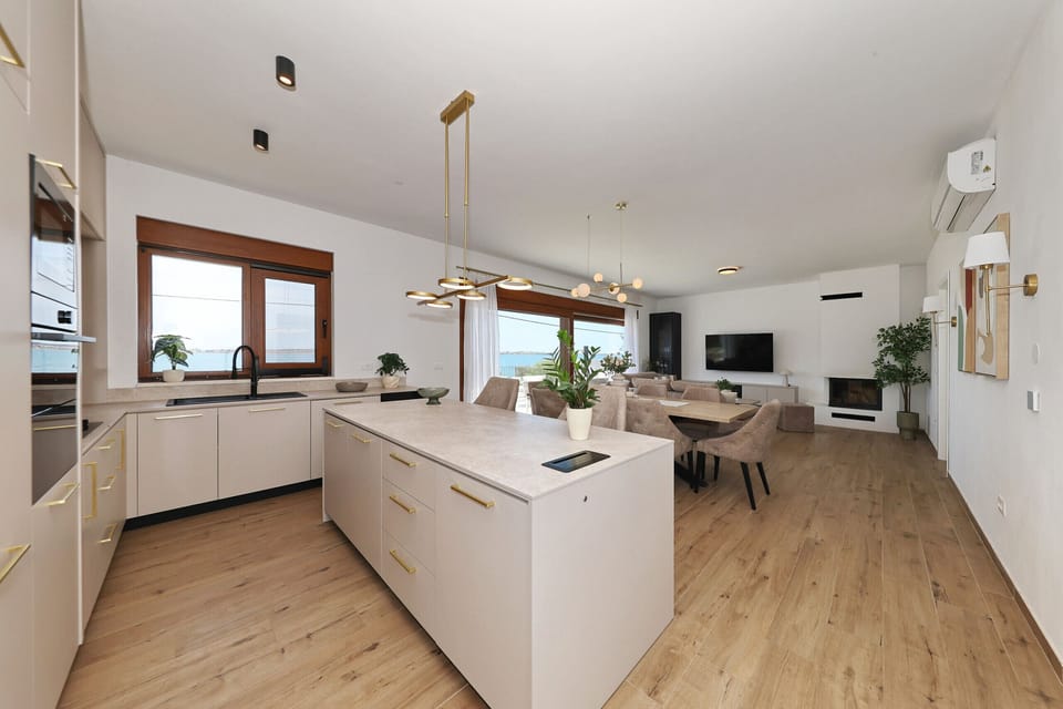 Open kitchen of Villa Diaria with kitchen island, dining area and view into the modern living room.