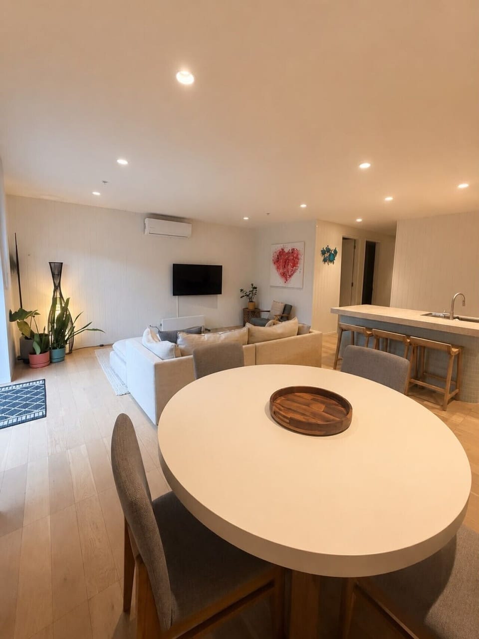 Relax in the light-filled living space with comfortable seating, smart TV, and seamless flow to the kitchen and dining areas.