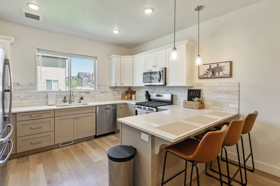Bright modern kitchen with island seating, stainless appliances, and airy design