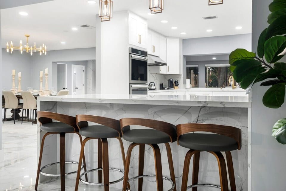 Waterfall edge marble kitchen island equipped with four modern wooden bar stools