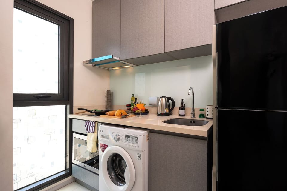 【Kitchen Counter】Everything you need for real cooking is laid out and ready. Induction hob, frying pan, saucepan, cutting board, knives, kettle, bowls, and condiments. The light blue glass backsplash keeps the kitchen feeling clean.