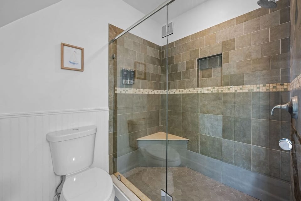 Modern spa-style bathroom with walk-in glass shower and tiled bench