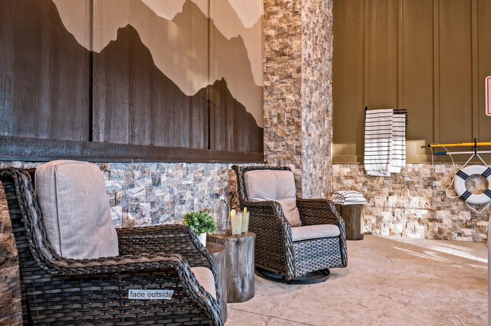 Cozy covered lounge with wicker seating and warm rustic stone accents