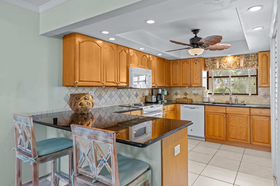 Breakfast Bar: Two cushioned stools tuck under a curved granite peninsula, opening the kitchen to the living space so the cook is never out of the conversation.