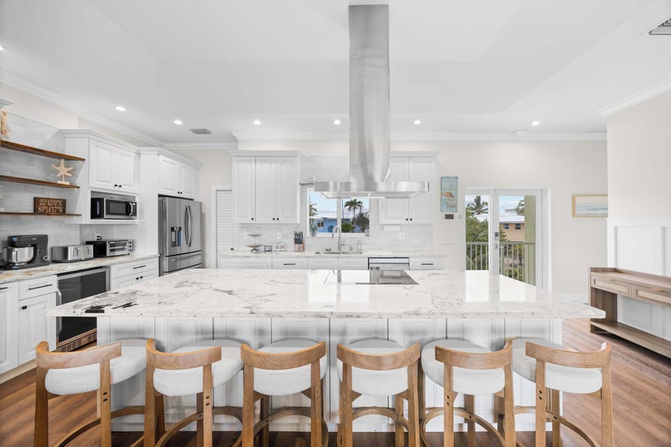 Chef's Kitchen: An oversized marble island with six stools and a pro-style hood.