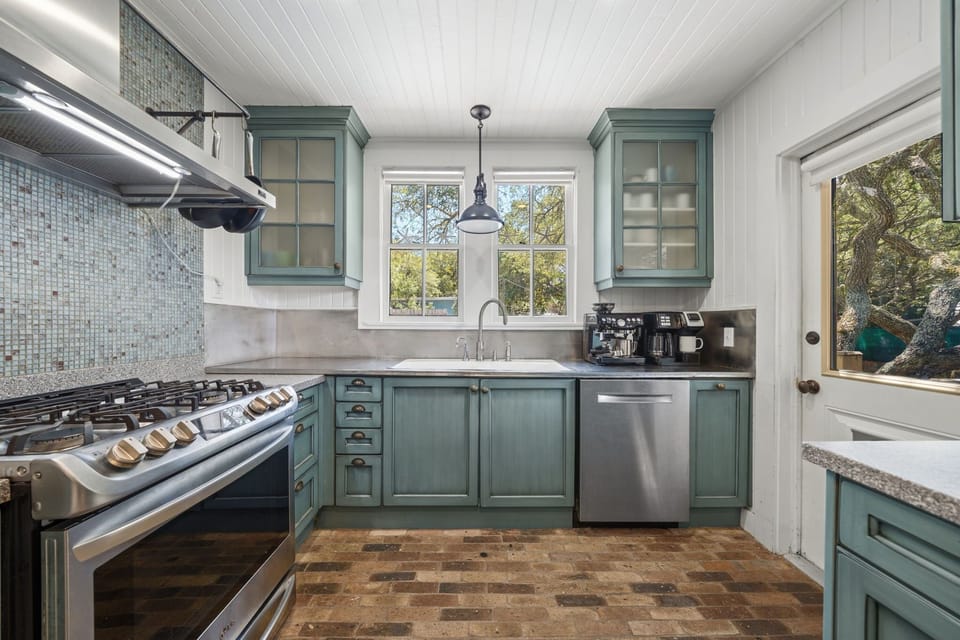 A gas range, full-size fridge, and generous counter space make this kitchen a joy to cook in, with bright views over the backyard and pool.