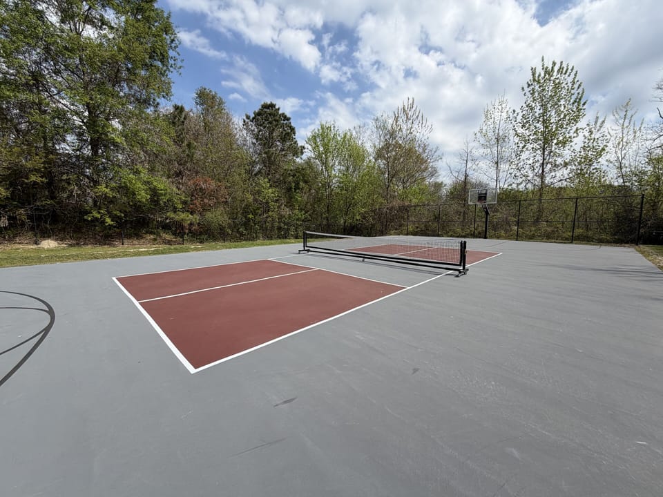 Private outdoor tennis/pickleball court surrounded by peaceful greenery
