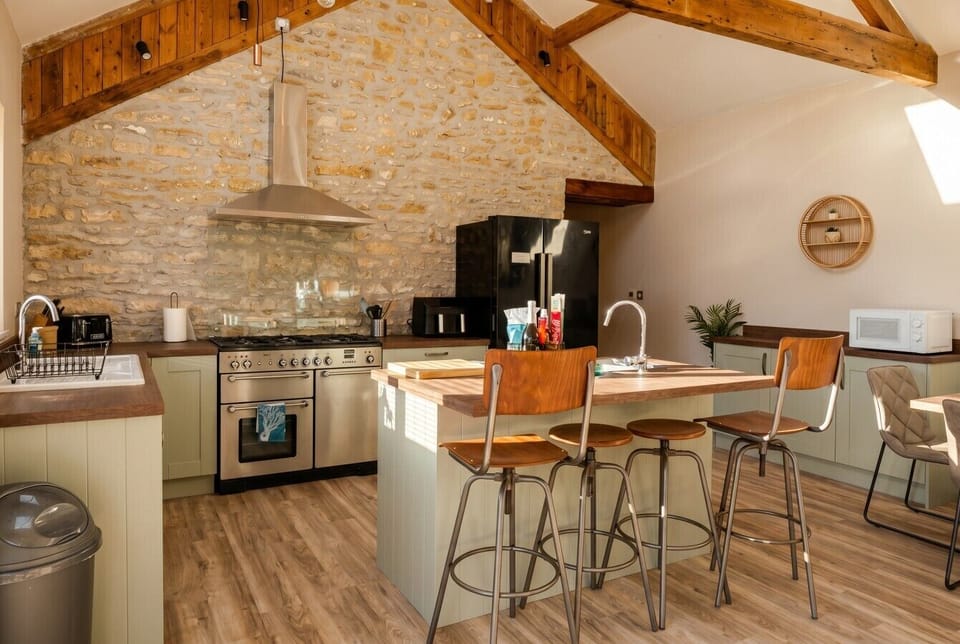 Characterful kitchen with range cooker, island and original stone barn wall.