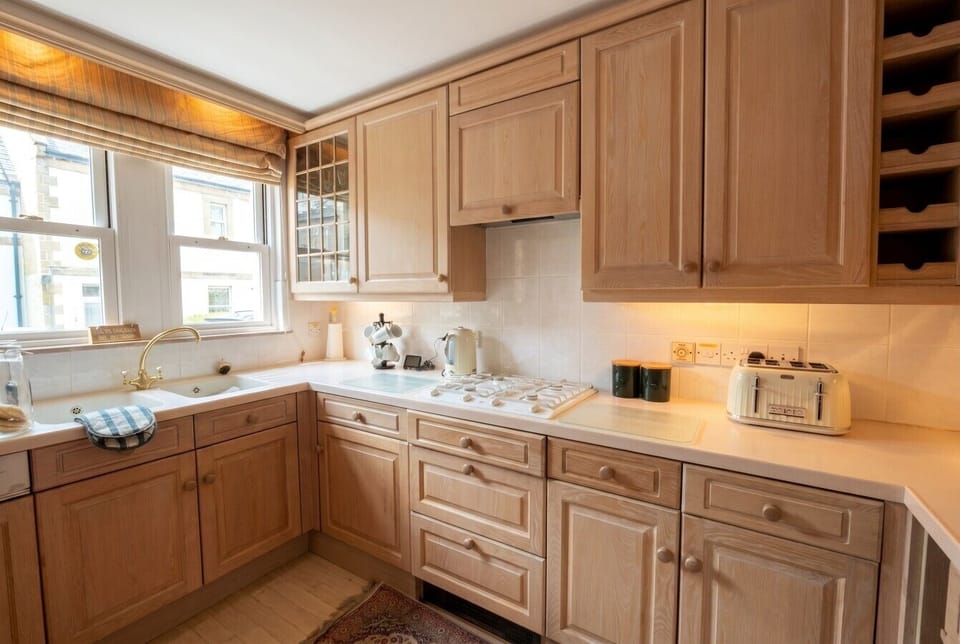 Bright fitted kitchen with gas hob and garden views over the sink.
