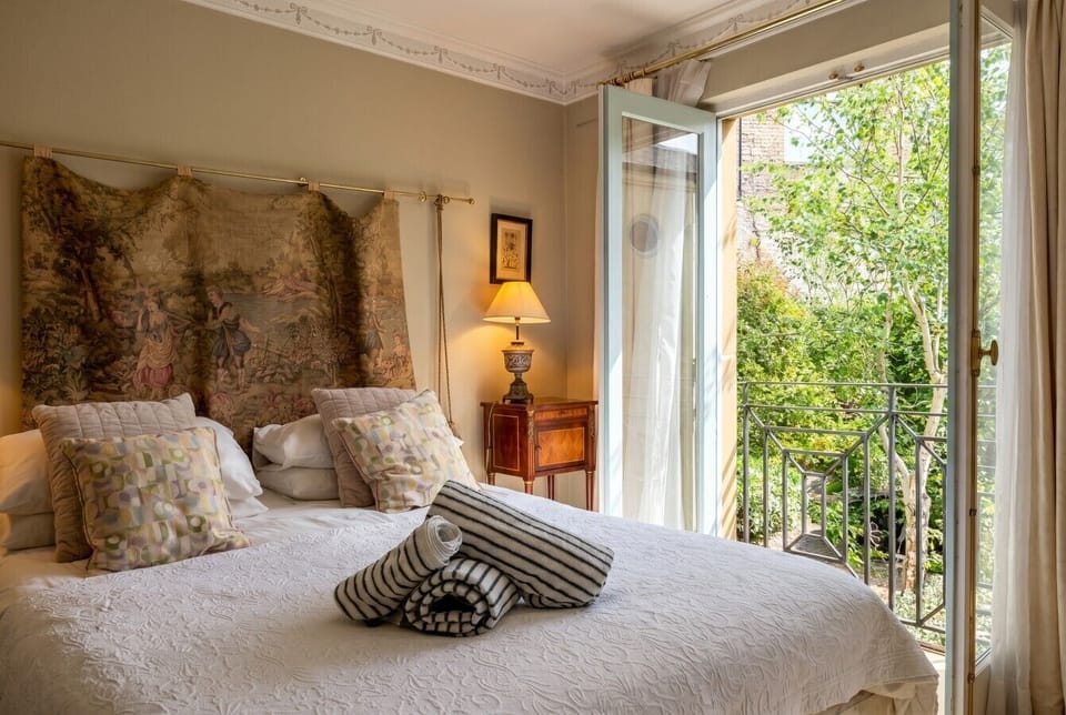 Throw open the French doors to leafy green views from this elegant bedroom.