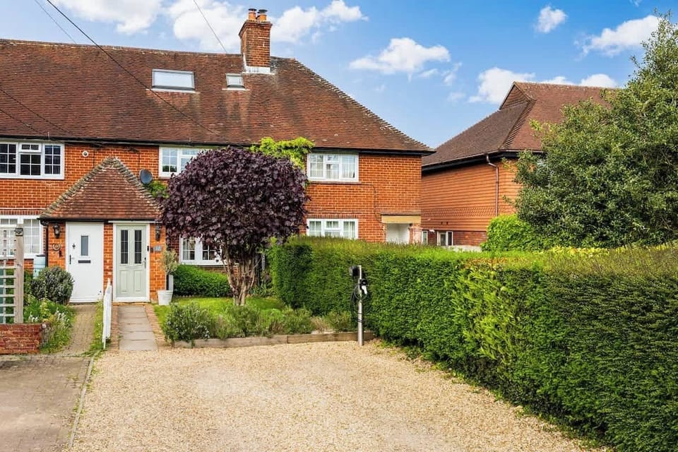Suburban Charm
A charming red-brick semi-detached home featured in image_ddfe87.png. Combining a neat gravel driveway, manicured green hedges, and a striking purple feature tree, this exterior exudes classic, picturesque curb appeal.